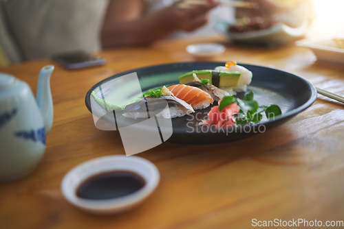 Image of Sushi, food and chopsticks in a chinese restaurant closeup for fine dining or traditional cuisine. Salmon, menu and seafood with an asian dish on a table in a local eatery for hunger or nutrition