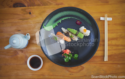 Image of Sushi, seafood and chopsticks in a chinese restaurant from above for fine dining or traditional cuisine. Salmon, menu and food with an asian dish on a table in a local eatery for hunger or nutrition