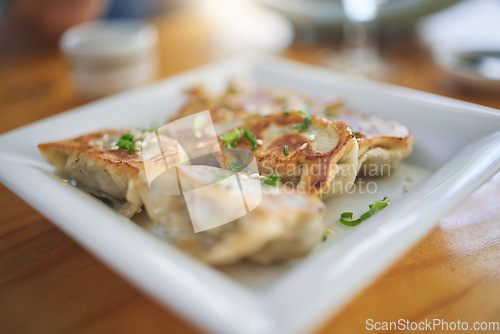 Image of Closeup, plate and dumplings for lunch at a restaurant, Chinese food or Asian cuisine. Zoom, protein and dinner on a table at a cafe for fine dining, eating or an appetizer or enjoying a meal