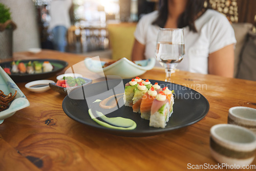 Image of Table, eating and people with sushi at a restaurant for fish, Chinese food or hungry. Closeup, plate and a person with seafood, lunch or dinner at a fine dining cafe for Asian cuisine or health