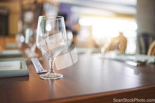 Image of Bokeh, lunch and glass on a table at a restaurant for water, alcohol or wine. Dinner, crystal and tableware for a drink at a coffee shop or cafe during dinner for a luxury and fine dining experience