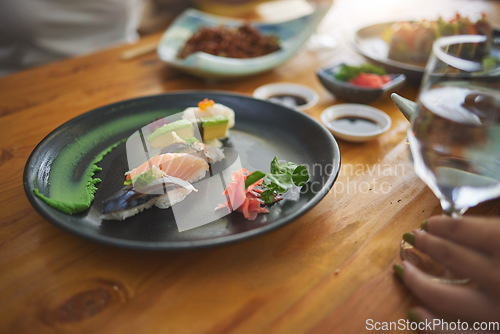 Image of Plate, table and sushi with a person at a restaurant for fish, lunch or seafood dinner. Closeup, hungry and people at a cafe for fine dining, Chinese food or eating Asian cuisine for a meal together