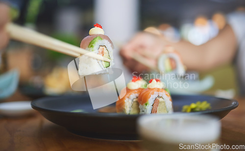 Image of Chopsticks, food and eating sushi at a restaurant for nutrition at table. Closeup of hungry people with wooden sticks and soy sauce for dining, Japanese culture and cuisine with creativity on a plate