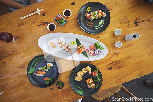 Image of Sushi, seafood and chopsticks in an asian restaurant from above for fine dining or traditional cuisine. Salmon, menu and chinese food with a dish on a table in a local eatery for hunger or nutrition