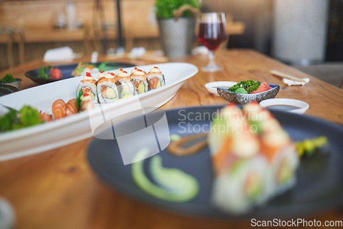 Image of Sushi, chinese food and chopsticks in an asian restaurant closeup for fine dining or traditional cuisine. Salmon, menu and seafood with a dish on a table in a local eatery for hunger or nutrition