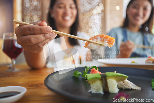 Image of Japanese woman, chopsticks and nigiri in restaurant, smile and excited for fine dining at party. Asian friends, fish and healthy with culture, traditional and fast food in diner, sushi bar or store