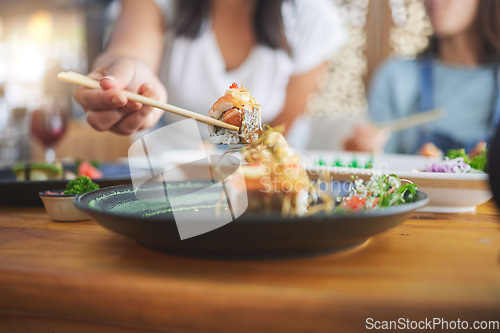 Image of Sushi, hand and eating food with chopsticks at a restaurant for nutrition and health. Closeup of a hungry people with wooden sticks for dining, Japanese culture and cuisine with creativity on plate