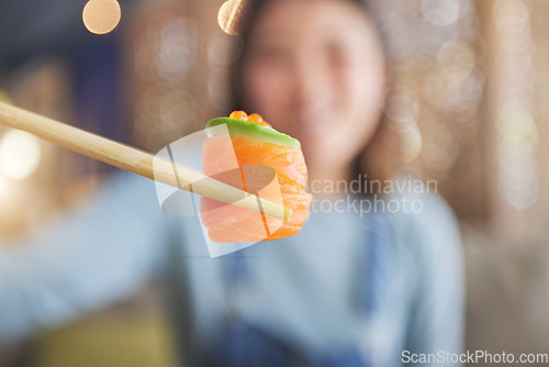 Image of Food, eating sushi and person with chopsticks at restaurant for nutrition and health. Closeup of a woman with wooden sticks for dining, Japanese culture and salmon cuisine with creativity on fish