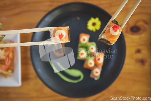 Image of Sushi, seafood and chopsticks in a chinese restaurant from above for dining or traditional cuisine. Salmon, menu and raw food with am asian dish on a table in a local eatery for hunger or nutrition