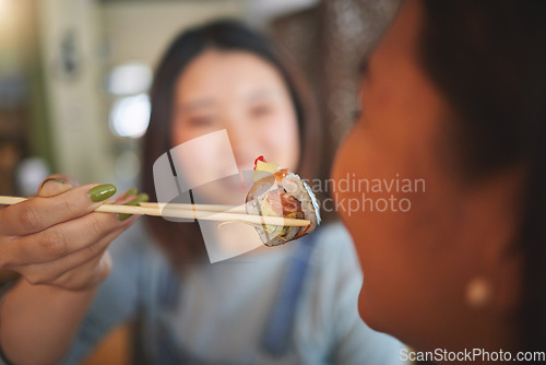 Image of Chopsticks, restaurant feeding and friends hands with sushi and Asian cuisine eating at cafe. Happy, hungry women and plate of food at Japanese bar with friendship, smile and bonding from table meal