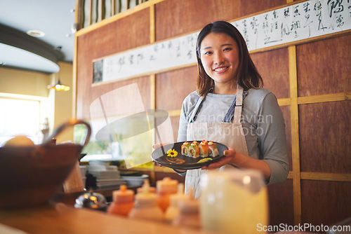 Image of Sushi restaurant, portrait and female waitress with a plate for serving a food order with a smile. Happy, lunch and young Asian server with Japanese recipe or meal at a traditional cuisine cafe.