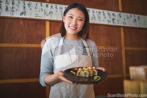 Image of Restaurant, portrait and female waitress with sushi for serving a food order with a smile. Happy, lunch and young Asian server with a plate of a Japanese recipe or meal at a traditional cuisine cafe.