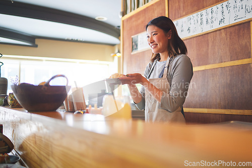 Image of Chinese food, waitress and an asian woman in a sushi restaurant to serve a traditional meal for nutrition. Kitchen, smile and cooking with a happy young employee in an eatery for fine dining cuisine