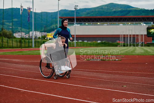 Image of A Muslim woman in a burqa running together with a woman in a wheelchair on the marathon course, preparing for future competitions.