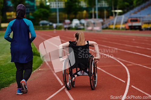 Image of A Muslim woman in a burqa running together with a woman in a wheelchair on the marathon course, preparing for future competitions.