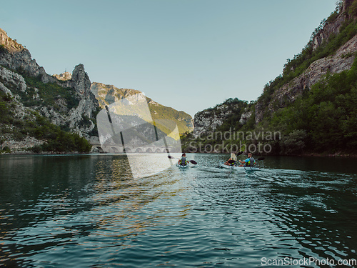 Image of A group of friends enjoying having fun and kayaking while exploring the calm river, surrounding forest and large natural river canyons