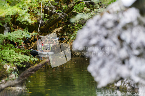 Image of A young couple enjoying an idyllic kayak ride in the middle of a beautiful river surrounded by forest greenery