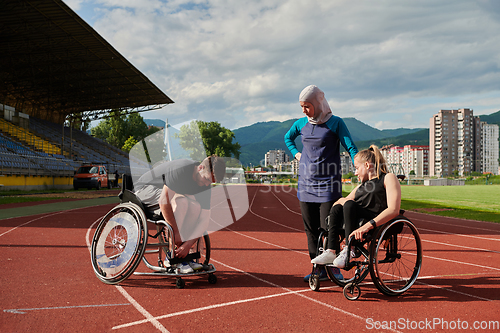 Image of A woman with a disability in a wheelchair talking after training with a woman wearing a hijab and a man in a wheelchair