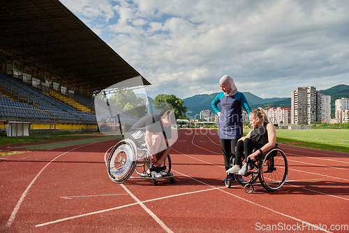 Image of A woman with a disability in a wheelchair talking after training with a woman wearing a hijab and a man in a wheelchair