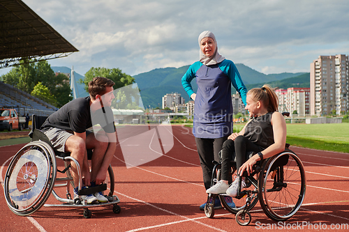 Image of A woman with a disability in a wheelchair talking after training with a woman wearing a hijab and a man in a wheelchair