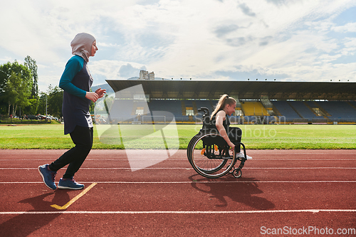 Image of A Muslim woman in a burqa running together with a woman in a wheelchair on the marathon course, preparing for future competitions.