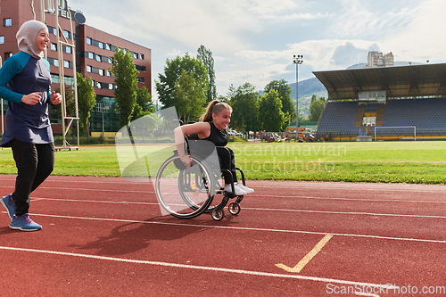 Image of A Muslim woman in a burqa running together with a woman in a wheelchair on the marathon course, preparing for future competitions.