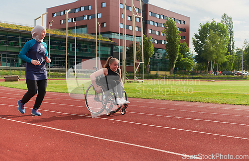 Image of A Muslim woman in a burqa running together with a woman in a wheelchair on the marathon course, preparing for future competitions.