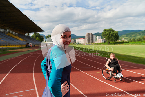 Image of A Muslim woman wearing a burqa resting with a woman with disability after a hard training session on the marathon course