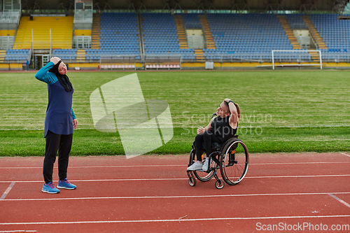 Image of Two strong and inspiring women, one Muslim in a burka and the other in a wheelchair stretching necks while on the marathon course