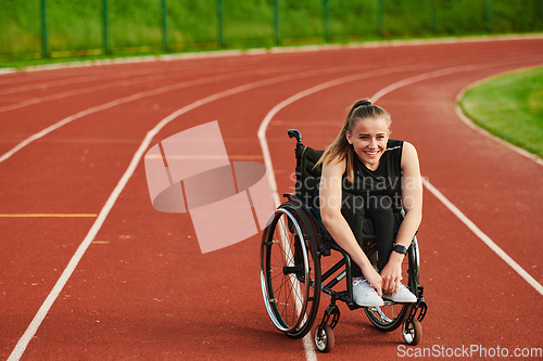 Image of A smiling woman with disablitiy sitting in a wheelchair and resting on the marathon track after training