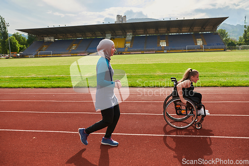 Image of A Muslim woman in a burqa running together with a woman in a wheelchair on the marathon course, preparing for future competitions.