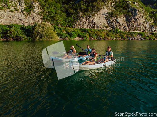 Image of A group of friends enjoying fun and kayaking exploring the calm river, surrounding forest and large natural river canyons during an idyllic sunset.