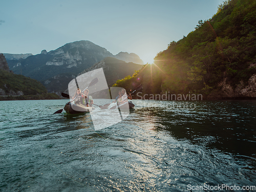 Image of A group of friends enjoying fun and kayaking exploring the calm river, surrounding forest and large natural river canyons during an idyllic sunset.