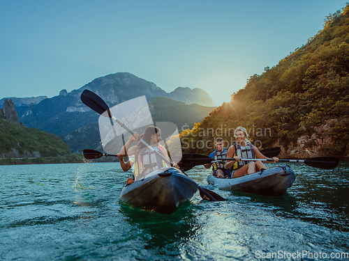 Image of A group of friends enjoying fun and kayaking exploring the calm river, surrounding forest and large natural river canyons during an idyllic sunset.