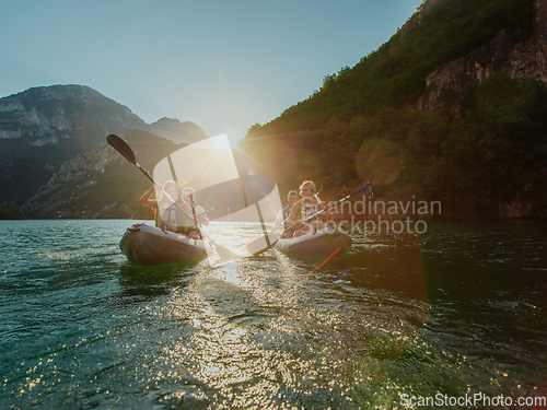 Image of A group of friends enjoying fun and kayaking exploring the calm river, surrounding forest and large natural river canyons during an idyllic sunset.