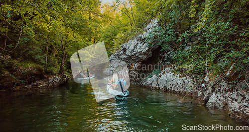 Image of A group of friends enjoying having fun and kayaking while exploring the calm river, surrounding forest and large natural river canyons