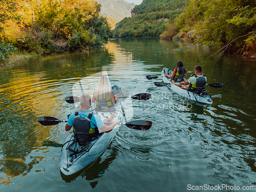 Image of A group of friends enjoying having fun and kayaking while exploring the calm river, surrounding forest and large natural river canyons