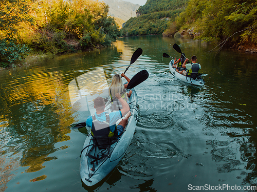 Image of A group of friends enjoying having fun and kayaking while exploring the calm river, surrounding forest and large natural river canyons