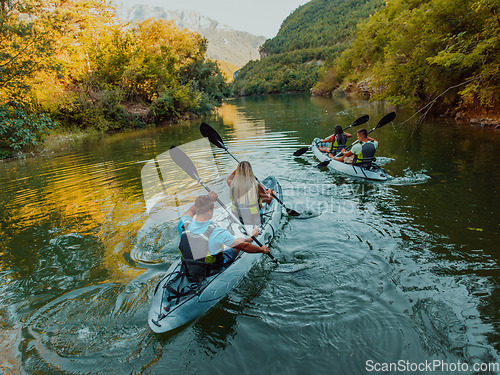 Image of A group of friends enjoying having fun and kayaking while exploring the calm river, surrounding forest and large natural river canyons