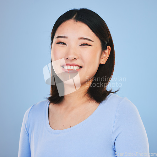 Image of Happy, smile and portrait of Asian woman in a studio with a natural, makeup and beauty face. Self care, cosmetics and headshot of a young female model with a cosmetology routine by a blue background.