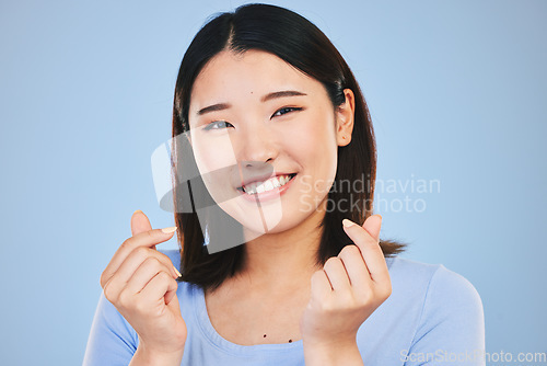 Image of Happy asian woman, portrait and love sign or hand gesture in romance against a blue studio background. Face of female person smile in happiness with loving emoji, icon or symbol for valentines day