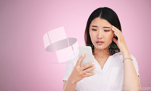 Image of Space, phone and stress with face of woman in studio for networking, communication and worry. Social media, news and frustrated with asian person on pink background for technology, scam and mockup