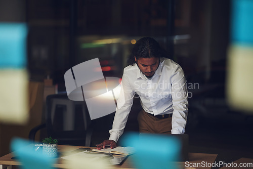 Image of Business man, night and planning in office, documents and reading for proposal, goals or deadline for report. Entrepreneur, paperwork and glass for sticky note, thinking and ideas in dark workplace