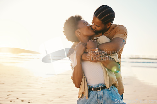 Image of Beach sunset, sunshine and black couple hug, kiss and enjoy time together, support and romance on travel holiday. Marriage, flare or hugging African people connect, care and bond on anniversary break