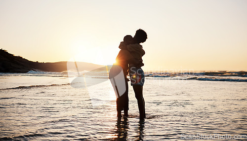 Image of Beach, sunset and silhouette of couple hug, connect and enjoy romantic time together, bonding and relax in sea water. Dark shadow, summer love or outdoor people embrace on tropical marriage honeymoon