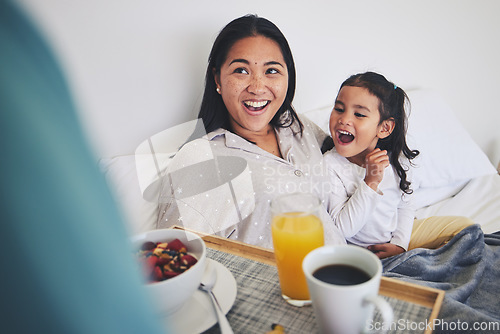 Image of Mother and child with breakfast in bed in the bedroom for mothers day surprise at home. Happy, smile and young mom relaxing with girl kid with a healthy meal for brunch on a weekend at their house.