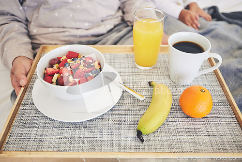 Image of Tray, hands and closeup of healthy breakfast in bed in the room of modern house on a weekend. Morning, diet and zoom of cereal with fruit, orange juice and cup of coffee for mother and child at home.