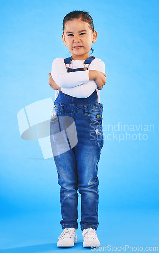 Image of Frustrated, child and arms crossed with tantrum in studio with mockup space. Kid, young girl and angry with cross frown and rejection with youth and mad attitude with blue background and grumpy