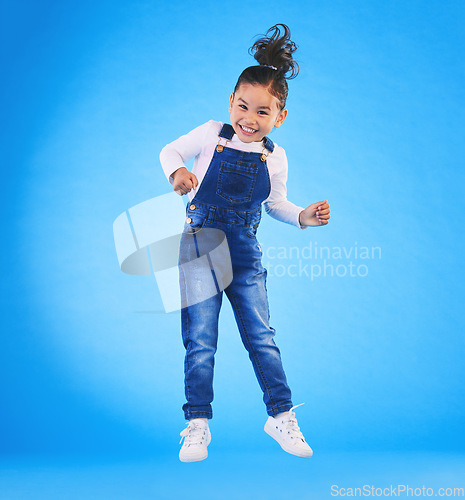 Image of Happy, jumping and portrait of a child in a studio with excitement, joy or wow expression. Happiness, smile and full length of a girl kid model moving for good news isolated by a blue background.