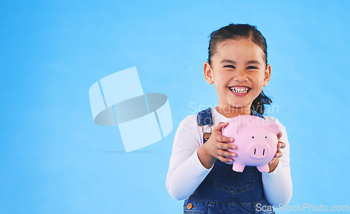 Image of Girl kid, piggy bank and studio portrait with mockup space, saving and financial education by blue background. Female child, money box and excited for goal, investing or learning discipline with cash